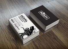 two black and white business cards sitting on top of a wooden floor next to each other