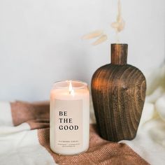 a white candle sitting on top of a bed next to a wooden vase with a pumpkin in it