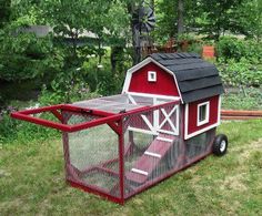 a red chicken coop sitting on top of a lush green field