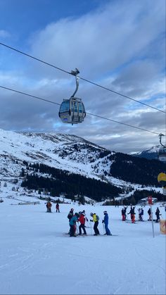 skiers and snowboarders at the bottom of a slope under a ski lift