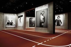 an indoor track with multiple black and white photos on the wall, including one man's torso