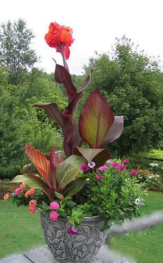 a vase filled with lots of flowers on top of a cement bench in the grass