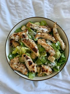 a bowl filled with chicken and lettuce on top of a white table cloth