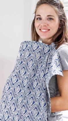 a woman holding up a blue and white blanket