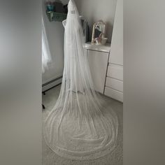 a wedding veil is hanging in the corner of a room with a dresser and mirror