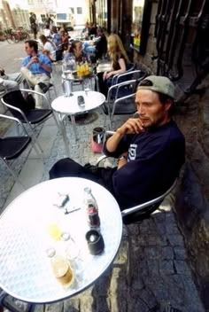 a man is sitting at an outdoor table with beer and sodas on the tables