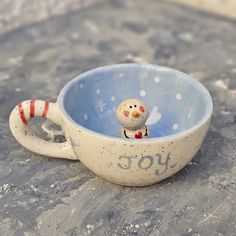 a ceramic bowl with a small bird in it and the word joy written on it