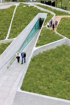 several people are walking up and down the stairs to an open area with grass growing on it