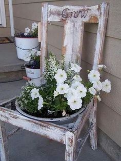 an old chair with flowers in it sitting on the front porch next to some potted plants