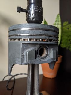 an old metal object on top of a wooden table next to a potted plant