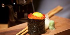 a sushi with gummy bears and chopsticks on a wooden table next to a coffee pot