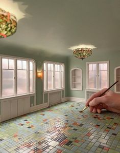 a hand holding a pen and drawing on a tiled floor in a room with windows