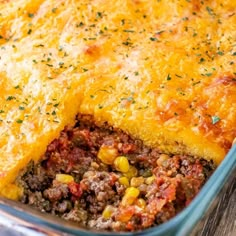 a casserole dish with meat, cheese and vegetables in it on a wooden table