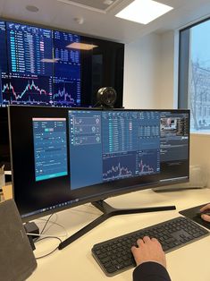 a man sitting at a desk in front of two computer monitors with graphs on them