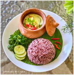 a white plate topped with rice, cucumbers and sauce