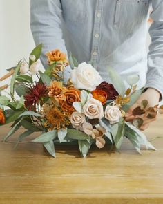 a person arranging flowers on a wooden table