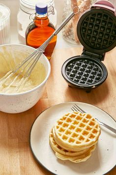 waffles and syrup sitting on a table with utensils in front of them