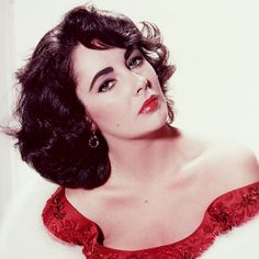 an old photo of a woman with dark hair wearing a red dress and large earrings