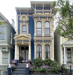 a blue and yellow house with flowers on the front yard in san francisco, california