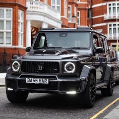 a black jeep driving down a street next to tall buildings