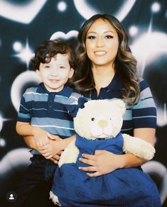 a woman holding a boy in front of a wall with bubbles and stars on it