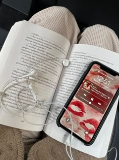 an open book with headphones on top of it next to a cell phone and earbuds