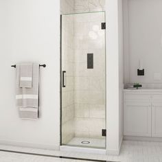 a white bathroom with a glass shower door and towel rack on the wall next to it