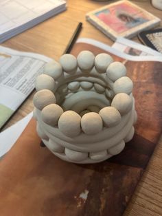 a white vase sitting on top of a wooden table next to papers and pencils