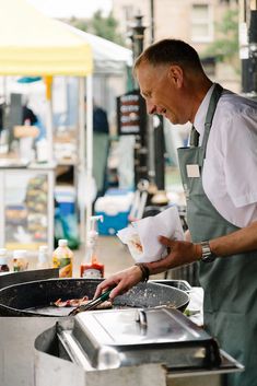 a man in an apron preparing food on a grill