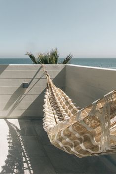 a hammock hanging from the side of a building next to the ocean on a sunny day