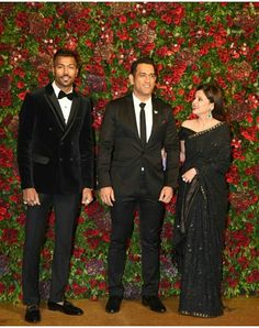 two men and a woman standing in front of a floral wall