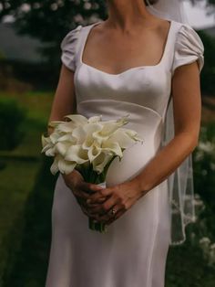 a woman in a white dress holding a bouquet of flowers