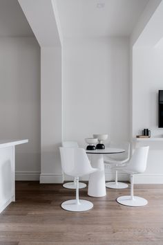 white chairs and tables in a room with wood flooring near a tv on the wall