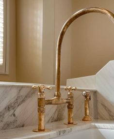 a bathroom sink with two faucets and marble counter top next to a window