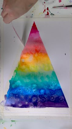 an art project with watercolors on paper and paint chips in the shape of a triangle