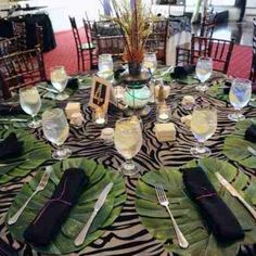 the table is set with silverware and black napkins, which are decorated with green leaves