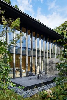 a house that is surrounded by trees and grass with glass walls on the outside side