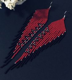 two red and black beaded earrings sitting on top of a table next to popcorn