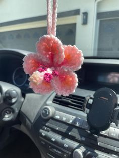 a car dashboard with a cell phone hanging from it's center console and an air vent in the background