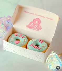 two donuts with frosting and sprinkles in a box