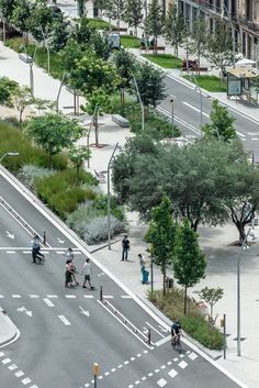 an aerial view of people walking and riding bikes on a city street with tall buildings in the background