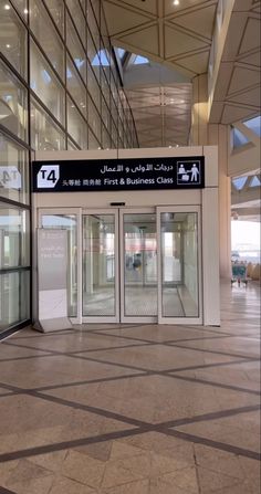 an empty lobby with glass doors and signs on the side of the building in arabic writing