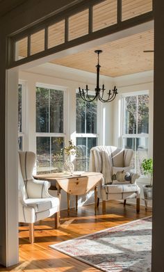 the sun shines through two windows into a living room with chairs and a table