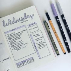 an open notebook with some pens on it