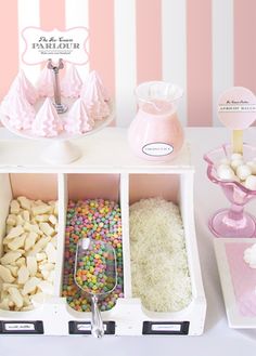 an assortment of sweets and candies on a table with pink striped wall behind it