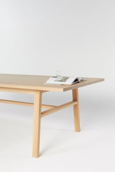 a wooden table with an open magazine on it's top, against a white background