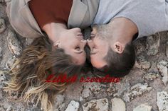 a man and woman laying on the ground with their heads touching each other's foreheads