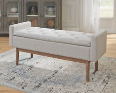 a white bench sitting on top of a rug in a living room next to a window