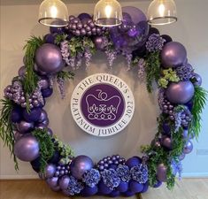 a circular wreath with purple ornaments and greenery on the bottom, in front of a sign for the queen's diamond jubilee