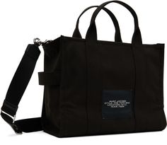 Cotton canvas tote in black. · Twin rolled carry handles · Adjustable and detachable shoulder strap · Text and logo printed at face · Canvas loop at side · Logo patch at back face · Zip closure · Patch pockets at interior · Zip pocket · Unlined · Logo-engraved silver-tone hardware · H10 x W13.25 x D6.5 Supplier color: Black Black Bags With Logo Hardware For Everyday, Black Travel Bags With Logo Hardware, Everyday Black Bag With Logo Hardware, Everyday Black Bags With Logo Hardware, Canvas Tote Shoulder Bag With Logo Hardware, Shopping Canvas Bag With Logo Hardware, Shopping Bags With Logo Hardware On Canvas, Canvas Shoulder Bag With Logo Hardware For Shopping, Everyday Canvas Shoulder Bag With Logo Hardware